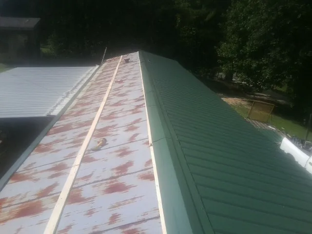 Old rusted panels beside newly installed green metal roofing — Wind Damage Roof Repair by Roofing Brothers in Lockhart